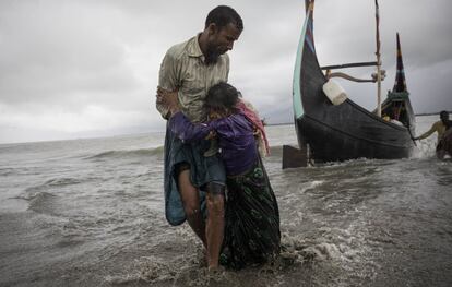 Un refugiado de la etnia Rohingya ayuda a una mujer anciana tras bajar del barco en el que viajaban desde Myanmar, en Dakhinpara (Banglads).