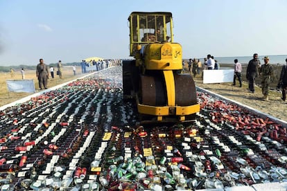 Un oficial paquistaní usa una apisonadora para destruir botellas de licor, en las afueras de Karachi (Paquistaní).