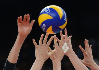 Los jugadores de Japón y Corea del Sur tratan de atrapar la pelota durante su partido de voleibol.