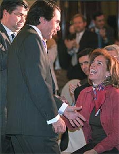 Aznar habla con su esposa, Ana Botella, en el acto de ayer.