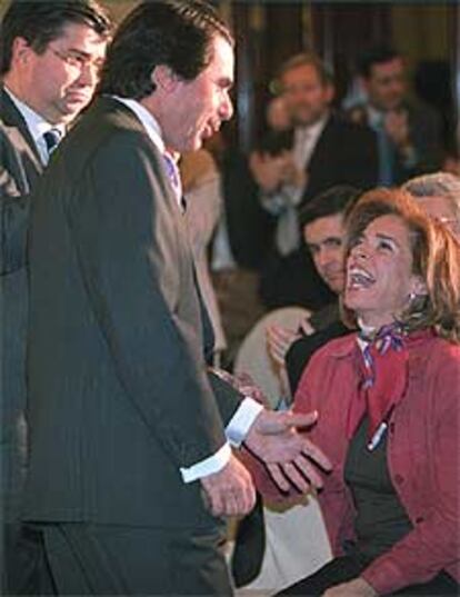 Aznar habla con su esposa, Ana Botella, en el acto de ayer.