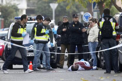 Varios policías nacionales observan el cuerpo de Rulber Delgado, tiroteado en la calle de Poniente en Coslada.