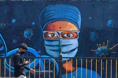 Un hombre pasa por delante de un mural que representa a un trabajador sanitario, en Bombay (India).