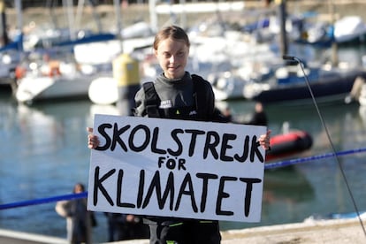 Greta Thunberg sujeta una pancarta en la que se puede leer "Skolstrejk för klimatet" (en sueco, huelga escolar por el clima), a su llegada a Lisboa a bordo del catamarán La Vagabonde. 