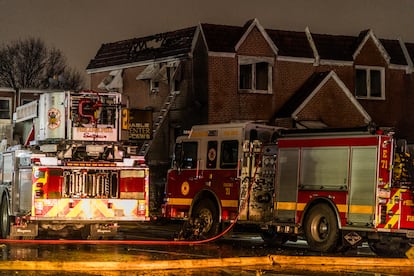 Bomberos trabajan en el tejado de una vivienda incendiada.