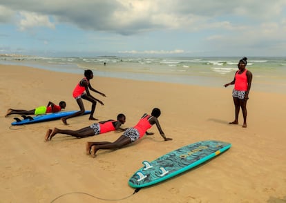 Khadjou Sambe enseña a sus alumnas los pasos clave que tienen que realizar para ponerse de pie desde la posición tumbada sobre la tabla, cuando vayan a coger una ola. Antes de practicar en el agua, conviene hacerlo en la arena para ganar seguridad. Playa de Yoff, Dakar, Senegal.