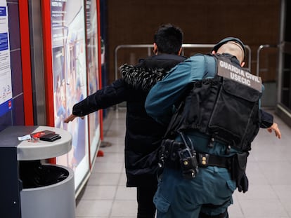 Un agente de la Guardia Civil cachea a un joven en una estación de Metro, en febrero en Madrid.