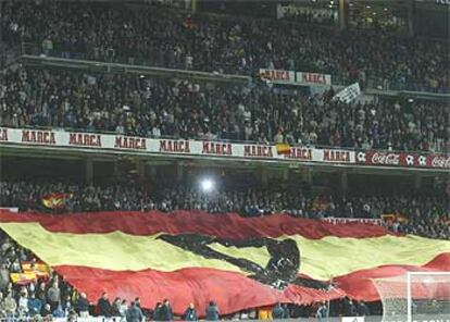 Una gran bandera de España, con un crespón negro, cubre las gradas del estadio Bernabéu.