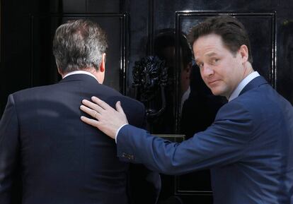 El liberal Nick Clegg pasa su manos sobre los hombros de David Cameron durante la entrada al 10 de Downing Street.