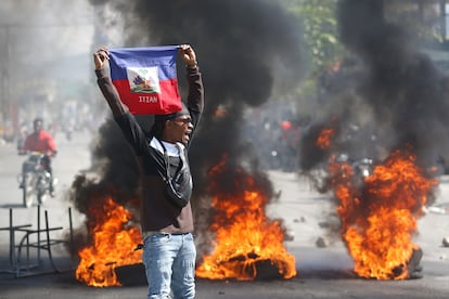 A demonstrator holds up an Haitian flag during protests demanding the resignation of Prime Minister Ariel Henry in Port-au-Prince, Haiti, Friday, March 1, 2024.