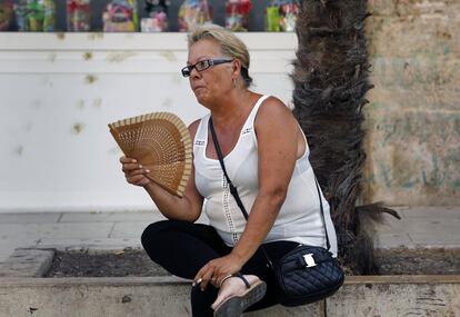 Una mujer descansa en una calle de Valencia.
