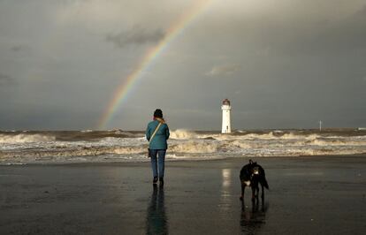 Una mujer pasea su perro junto al Faro de Perch Rocka frente a la playa de New Brighton, cerca de Wallasey en Gran Bretaña.