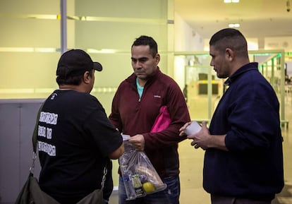 Felipe (d) y otro compañero reciben a un deportado en el aeropuerto.