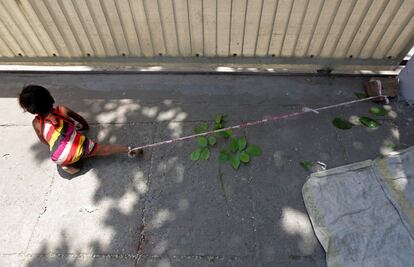 Barrier tape is tied around 15-month-old Shivani's ankle to prevent her from running away, while her mother Sarta Kalara works at a construction site nearby, in Ahmedabad, India, April 19, 2016. Kalara says she has no option but to tether her daughter Shivani to a stone despite her crying, while she and her husband work for 250 rupees ($3.8) each a shift digging holes for electricity cables in the city of Ahmedabad. There are about 40 million construction workers in India, at least one in five of them women, and the majority poor migrants who shift from site to site, building infrastructure for India's booming cities. Across the country it is not uncommon to see young children rolling in the sand and mud as their parents carry bricks or dig for new roads or luxury houses. REUTERS/Amit Dave       SEARCH "TIED TODDLER" FOR THIS STORY. SEARCH "THE WIDER IMAGE" FOR ALL STORIES      TPX IMAGES OF THE DAY