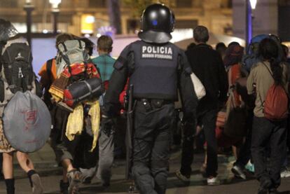 Varios acampados abandonan la plaza de Catalunya bajo la mirada de un <i>mosso.</i>