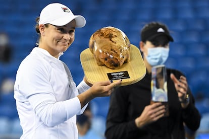 Barty posa con el trofeo de campeona, con Muguruza al fondo.