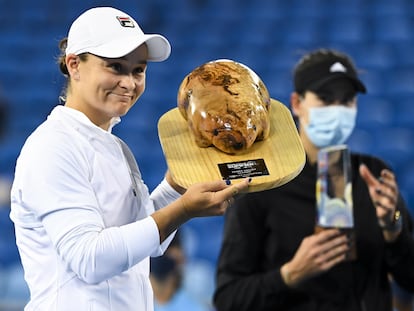 Barty posa con el trofeo de campeona, con Muguruza al fondo.