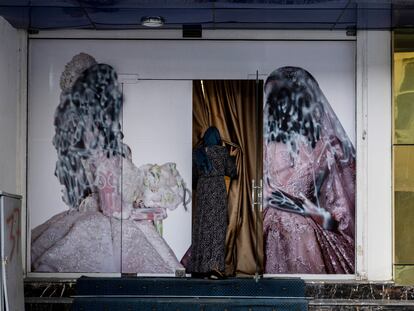 Una mujer entraba en un centro de estética de Kabul, cuyos carteles promocionales habían sido cubiertos de pintura para ocultar el rostro de las mujeres representadas en los dibujos, el 11 de septiembre de 2021.