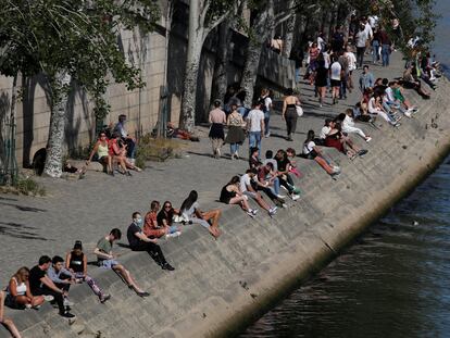 Personas sentadas a la orilla del Sena, en París, el domingo.
