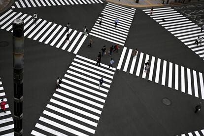 Varias personas con mascarillas cruzan un paso de peatones en el centro de Tokio. El país nipón ha levantado este lunes el estado de alarma sanitaria sobre las cinco últimas prefecturas, donde aún seguía vigente esta medida para luchar contra la pandemia de covid-19.
