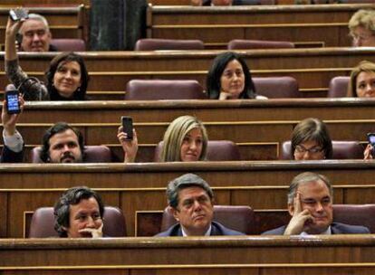 Algunos diputados del PP exhiben sus móviles. En primera fila, Floriano, Trillo y González Pons.