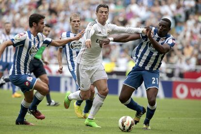 El delantero del Real Madrid Cristiano Ronaldo pelea un bal&oacute;n con los jugadores del Deportivo Juan Dom&iacute;nguez (i) y Modibo Diakit&eacute;.