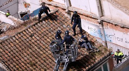 Efectivos antidisturbios del Cuerpo Nacional de Policía suben en una grúa para desalojar a dos personas que intentan impedir el derribo de la casa del Cabanyal.