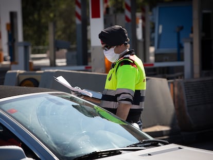 A Catalan regional police officer asks a driver to justify his trip at a toll plaza in La Roca del Vallès on Thursday, at the start of the Easter holiday. 
09/04/2020