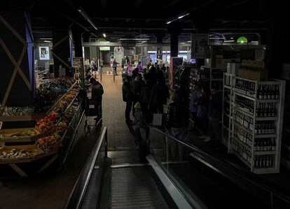 Varios ciudadanos hacen sus compras en un supermercado a oscuras, tras un ataque con misiles rusos, el 22 de octubre en Kiev.