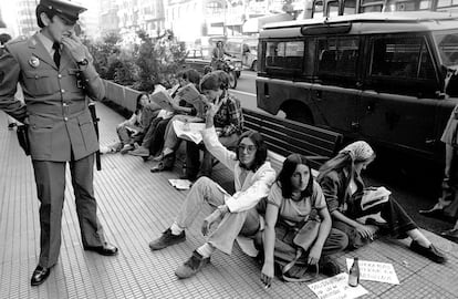 8 de octubre de 1976. Un agente de policía mira a un grupo de estudiantes encadenados a un banco de la Gran Vía de Madrid, en protesta por no haber sido admitidos en la facultad de Medicina de la Universidad Complutense.