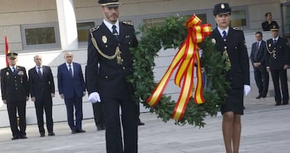 El ministro del Interior, Jorge Fernández Díaz, en segundo plano con traje azul, observa cómo dos policías nacionales depositan una corona en homenaje a los agentes muertos, esta mañana en San Sebastián.