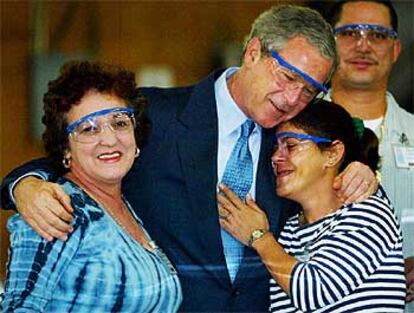 Bush abraza a dos empleadas durante su visita de ayer a una fábrica de componentes electrónicos en Tampa, Estado de Florida.