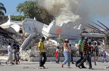 Um grupo caminha ao lado das ruínas em chamas do Ministério da Justiça, poucos dias após o terremoto (16/01/2010).