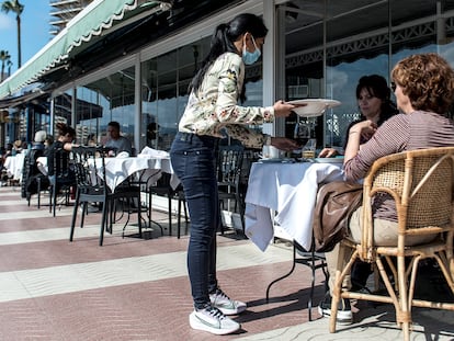 Una camarera atiende a clientes en el paseo marítimo de Palamós.