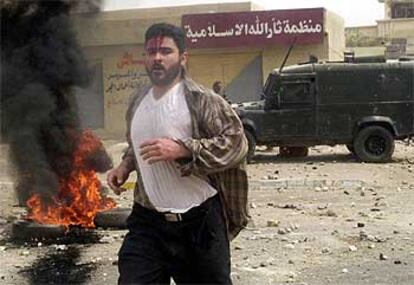 Un iraquí herido huye del lugar donde se han registrado los enfrentamientos con las tropas británicas.