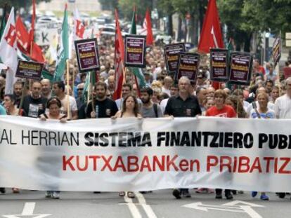 Ainhoa Etxaide y Txiki Muñoz tras la pancarta contra la privatización de Kutxabank