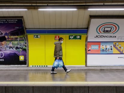 Un hombre, protegido con mascarilla, camina por un andén vacío del metro de Madrid.