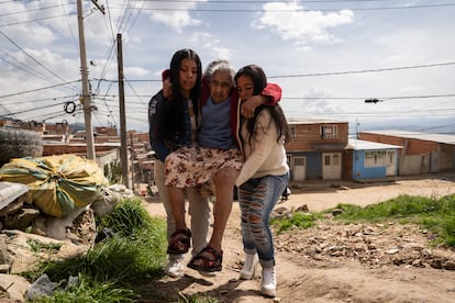 Karen Serrato y  Patricia Rodriguez, cargan la abuela Emperatriz Gutierrez, hasta subirla a la casa que queda en una pequeña colina.