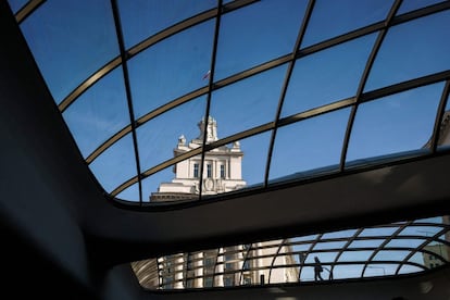 Un hombre es visto a través de un techo de vidrio mientras camina frente al edificio del parlamento búlgaro en el centro de Sofía.