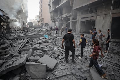 Un grupo de personas camina entre los escombros de edificios destruidos por un ataque israelí en Ciudad de Gaza, este viernes 8 de agosto de 2025.