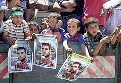 Varios niños muestran carteles con la imagen de un joven campesino muerto a manos del Ejército israelí, durante su entierro, ayer en Gaza.