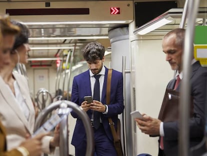 Varias personas usan sus móviles en el metro.