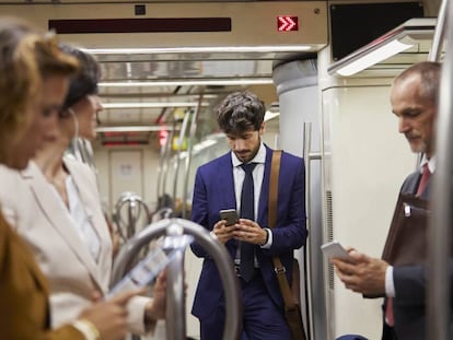 Varias personas usan sus móviles en el metro.