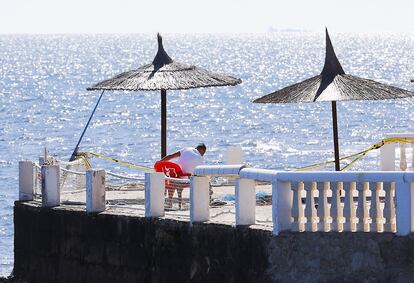 Un hombre realiza labores de mantenimiento en una terraza de playa en Dénia (Alicante).