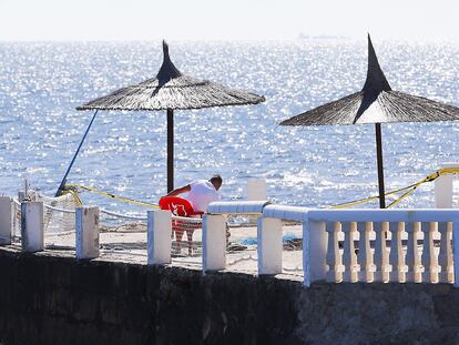 Un hombre realiza labores de mantenimiento en una terraza de playa en Dénia (Alicante).