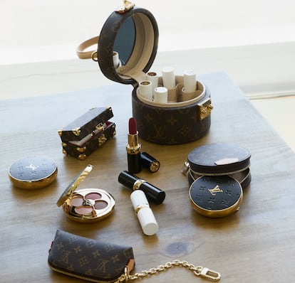 De arriba abajo, de izda. a dcha., cofre Scott en el que se pueden guardar cinco labiales, con varios de los bálsamos de la colección; minibaúl en lona Monogram; con carcasa negra, barras de labios LV Rouge y, blanca, LV Baume; paletas de sombras de ojos LV Ombre; estuche redondo para sombras en lona Monogram, y, debajo también en Monogram, funda para el labial. Todo de LOUIS VUITTON.