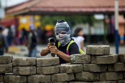 Um jovem com a cara tapada e um lança-chamas em uma barricada no bairro indígena de Monimbó, durante o dia 90º dia de protestos contra o governo de Daniel Ortega na cidade de Masaya (Nicarágua), no dia 15 de julho de 2018.