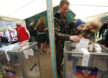 Un hombre vestido de paramilitar deposita su papeleta en una tienda de Donetsk.