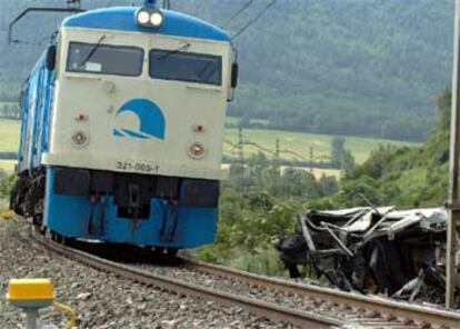 Una máquina del servicio de mantenimiento de RENFE pasa junto a los restos del todoterreno siniestrado.