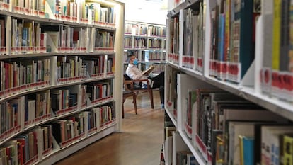 Un lector con mascarilla consulta un libro en una biblioteca de Singapur. / SUHAIMI ABDULLAH (GETTY IMAGES)